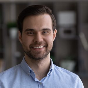 Headshot portrait of smiling young Caucasian man indoors